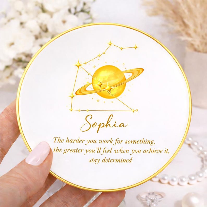 May include: White ceramic plate with a gold rim, featuring a golden planet design and the name "Sophia." The plate includes the text: "The harder you work for something, the greater you'll feel when you achieve it, stay determined."
