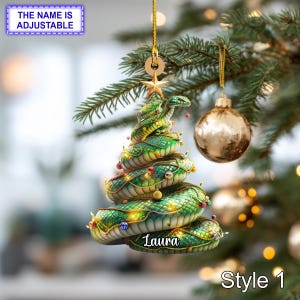 May include: A green and gold Christmas tree ornament shaped like a snake, with the name "Laura" on it. The ornament is decorated with lights and a star on top. The text "Style 1" is at the bottom. The text "THE NAME IS ADJUSTABLE" is at the top.