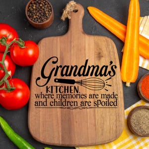 May include: Wooden cutting board with the text "Grandma's Kitchen. Where memories are made and children are spoiled." The board is surrounded by tomatoes, carrots, spices, and a green pepper.