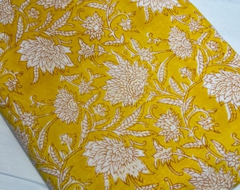 Tela de algodón amarilla con estampado floral blanco para vestidos.