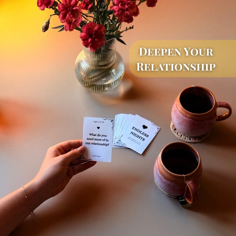 Endless Nights couples conversation starter cards being played at home with tea, flowers, and cozy setting. Card reads “What do you need more of in our relationship?” Perfect printable game for couples to deepen connection, improve communication, and spark intimacy. Designed for dating, engaged, or married partners as a romantic before-bed activity. Fun 30-day challenge with thoughtful questions for anniversaries, date nights, or long distance relationships.