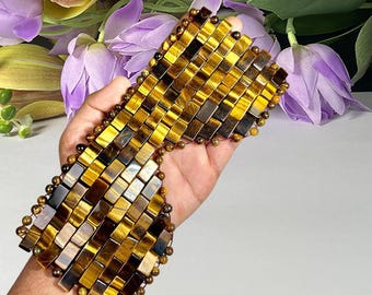 May include: A wide bracelet constructed from rectangular tiger's eye stone tiles arranged in a grid pattern, connected by small round tiger's eye beads. The stones feature golden-brown and dark brown chatoyant bands with a polished finish.