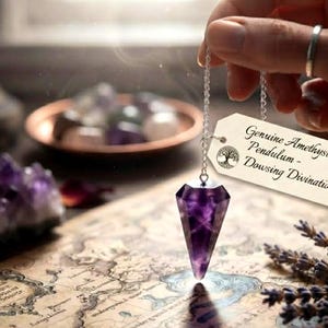May include: A faceted purple amethyst crystal pendulum suspended from a silver-toned chain. Attached to the chain is a rectangular tag with the text Genuine Amethyst Pendulum - Dowsing Divination and a circular tree graphic printed in black ink.