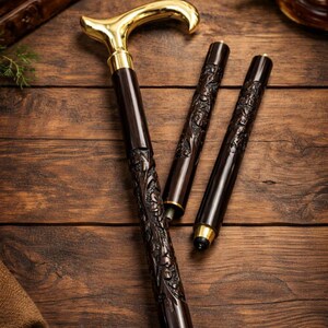 May include: A collapsible walking cane featuring a polished gold-tone handle and a dark brown shaft with intricate floral carvings. The cane is composed of three distinct segments that can be joined together, showcasing metallic threaded connectors.
