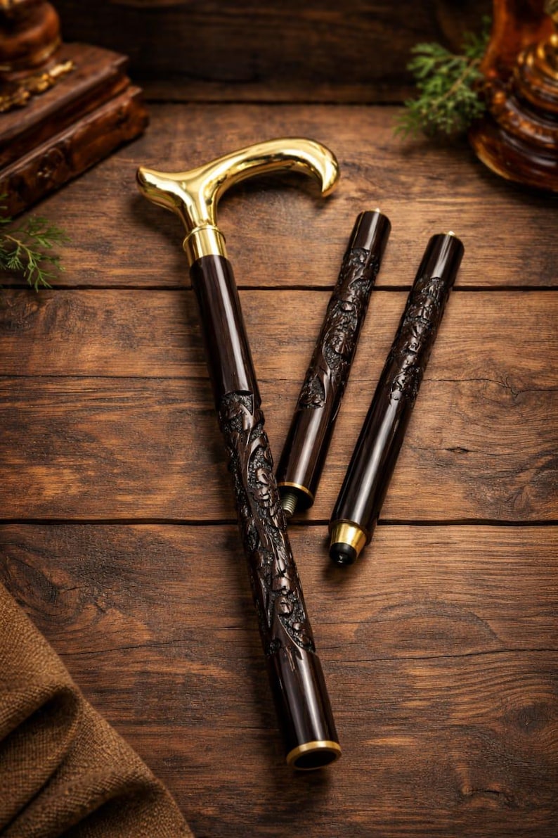May include: A collapsible walking cane featuring a polished gold-tone handle and a dark brown shaft with intricate floral carvings. The cane is composed of three distinct segments that can be joined together, showcasing metallic threaded connectors.