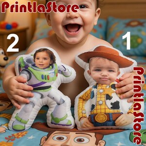 A baby is holding a plush toy of Buzz Lightyear and Woody from Toy Story, with a big smile on their face.