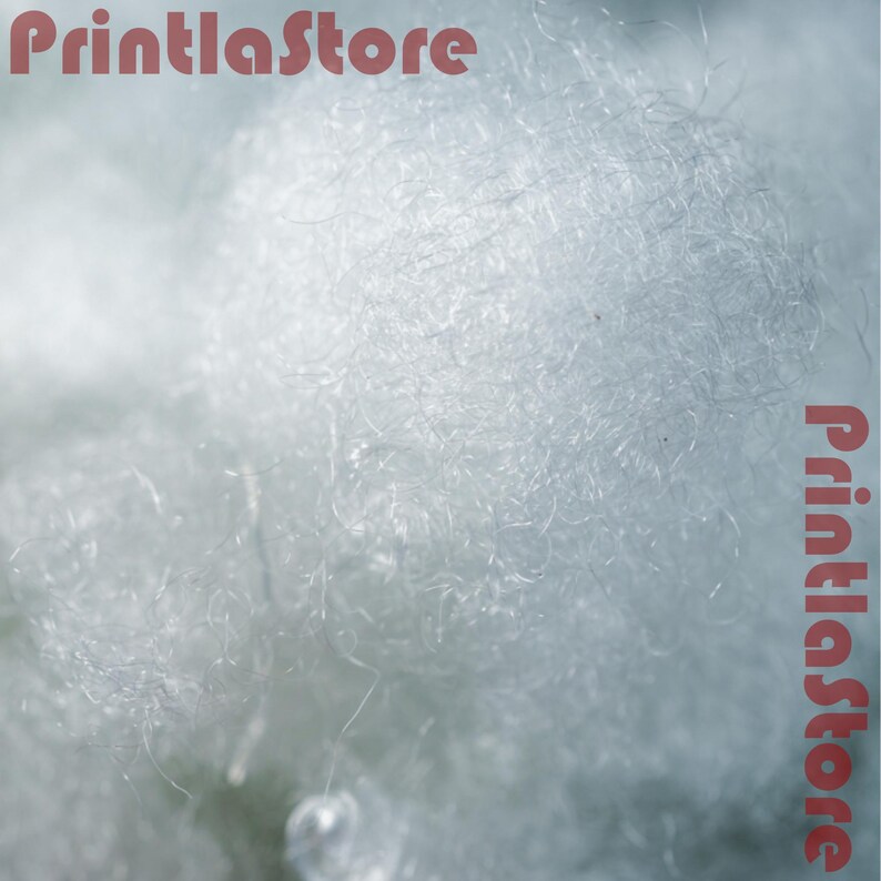 The image is a close-up of a fluffy, white material, possibly cotton or a similar soft fiber.