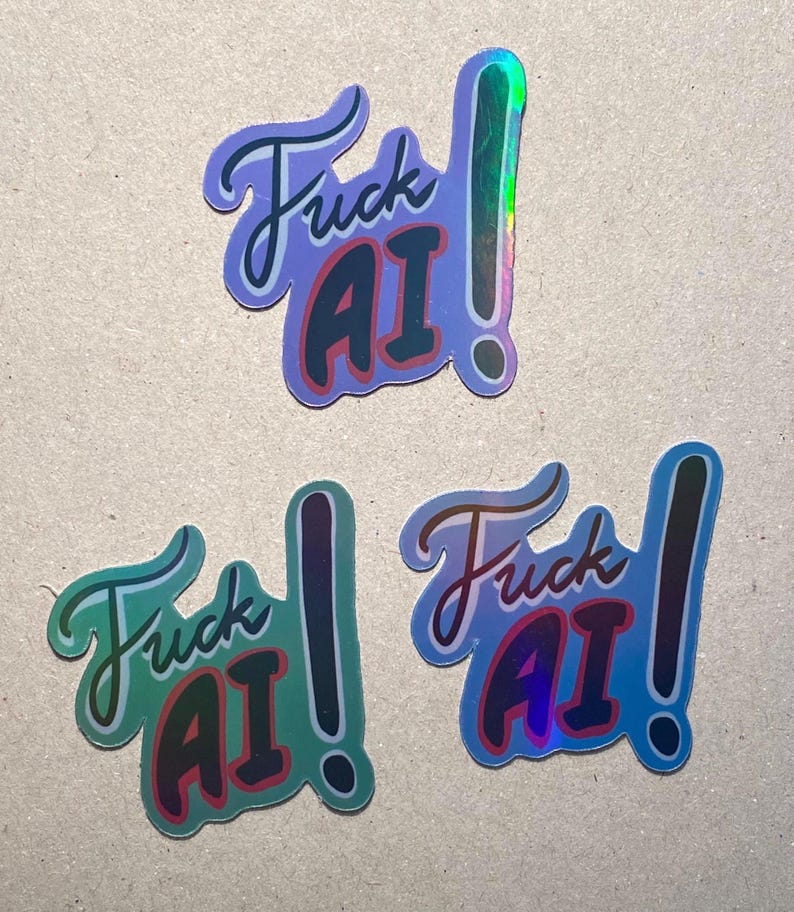 May include: Three holographic stickers with the text "Fuck AI" in a stylized font. The stickers have a gradient of colors, including blue, green, and pink, with a shiny, reflective finish. Each sticker features an exclamation point.