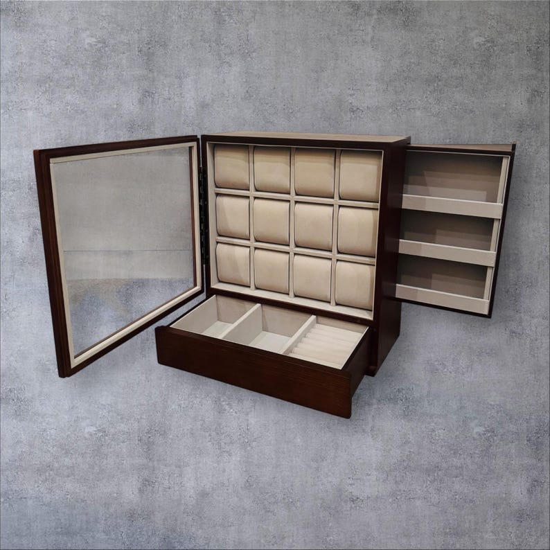 K&ouml;nnte beinhalten: Eine dunkelbraune Holz-Uhrenbox mit Glast&uuml;r und mehreren F&auml;chern. Der Innenraum verf&uuml;gt &uuml;ber beige Kissen f&uuml;r Uhren und zus&auml;tzlichen Stauraum. Die Box ist ge&ouml;ffnet und zeigt das Innere und die seitliche Aufbewahrung.