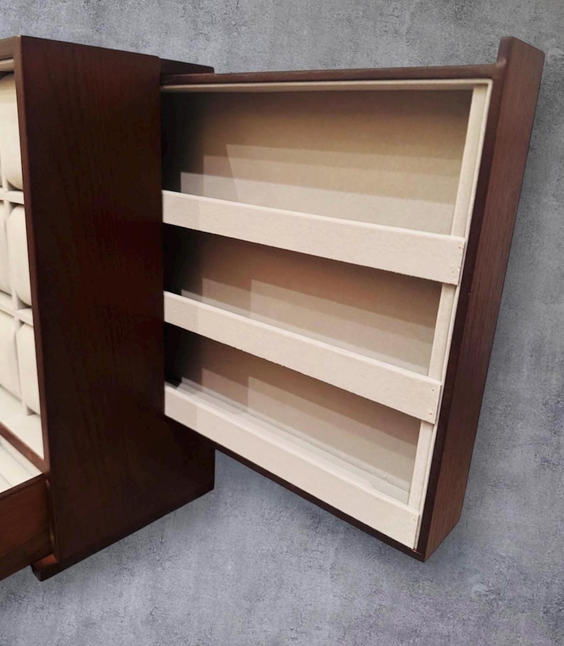 K&ouml;nnte beinhalten: Eine dunkelbraune Holzschmuckschatulle mit einer teilweise ge&ouml;ffneten Schublade, die drei cremefarbene Regale freilegt. Die Schatulle hat eine rechteckige Form und eine glatte Oberfl&auml;che mit hellem Innenraum.
