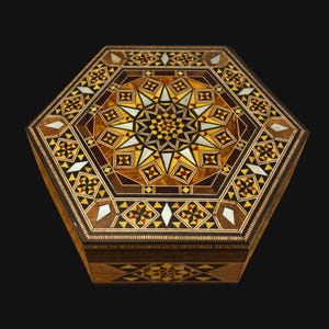 Pode incluir: Uma caixa hexagonal de madeira com intrincados padrões geométricos embutidos. A tampa apresenta um design de estrela central rodeado por formas menores em tons de castanho, amarelo e branco. É um objeto de armazenamento decorativo.