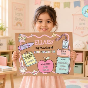 May include: A rectangular brown sign for the first day of kindergarten featuring the name Ellary, a pink apple, a purple crayon, and a blue notebook. The sign includes text fields for age, teacher name, career goals, and favorite activities with colorful illustrations.