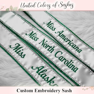 May include: White satin sashes with green embroidered text and rhinestone trim. The sashes read "Miss Alaska", "Miss North Carolina", and "Miss Americana". The text "United Colors of Sashes" and "Custom Embroidery Sash" are also visible.