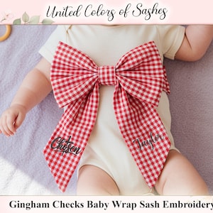 Könnte beinhalten: Ein Baby in einem cremefarbenen Body mit einer großen rot-weiß karierten Schleife. Auf der Schleife sind die Namen "Chosen" und "Taylor" gestickt. Der Text "United Colors of Sashes" ist oben zu sehen.