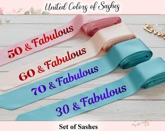 Op de afbeelding: Set van satijnen sjerpen in roze, crème en teal, elk bedrukt met "& Fabulous" en een andere leeftijd in rood of paars. De sjerpen zijn gelabeld met "30 & Fabulous", "50 & Fabulous", "60 & Fabulous" en "70 & Fabulous".