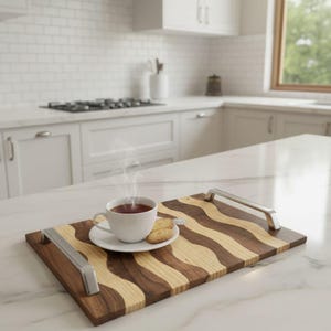 Puede incluir: Bandeja de madera con un patrón ondulado de madera clara y oscura. La bandeja tiene asas plateadas y contiene una taza de té blanca, un platillo y galletas. El vapor se eleva del té.