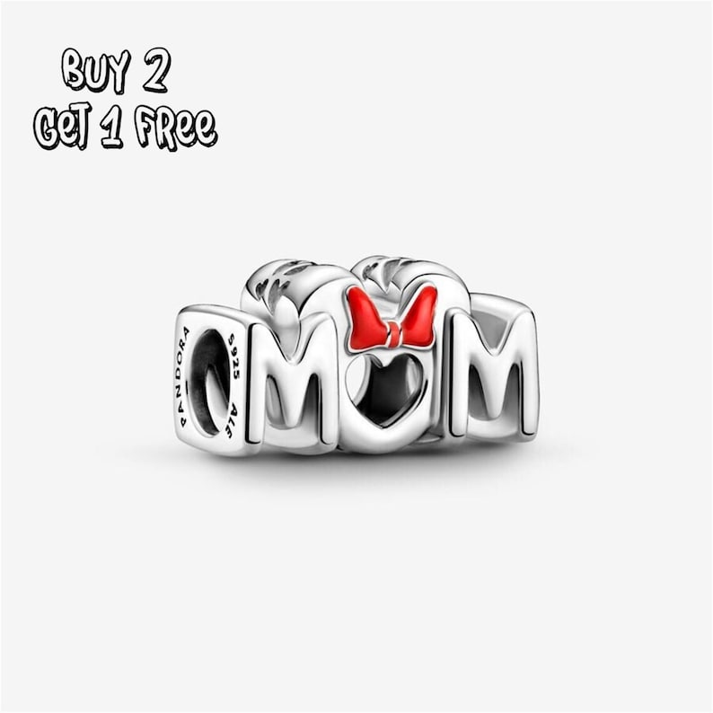 Pu&ograve; includere: Un charm in argento con la scritta "MOM", una "O" a forma di cuore e un fiocco rosso. Il charm &egrave; in argento e presenta il marchio "Pandora" e "S925 ALE" incisi sul lato. Il testo "BUY 2 GET 1 FREE" si trova nell'angolo in alto a sinistra.