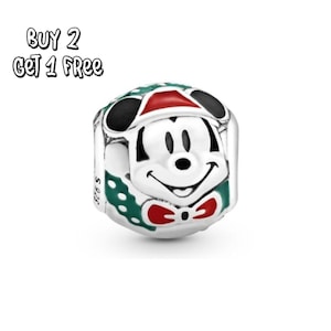 Pode incluir: Um berloque de prata com Mickey Mouse com chapéu e gravata borboleta de Natal. O berloque tem detalhes em preto, vermelho, verde e branco. O texto "BUY 2 GET 1 FREE" está no canto superior esquerdo.