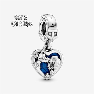 Pode incluir: Um berloque de prata com um pingente em forma de coração com um design de esmalte azul e um personagem de desenho animado. O berloque tem a marca Pandora e o texto "BUY 2 GET 1 FREE".