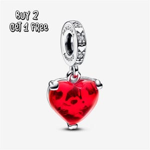 May include: A silver charm featuring a red heart-shaped pendant. The charm is engraved with the words "Pandora" and "Disney". The text "BUY 2 GET 1 FREE" is visible in the upper left corner.