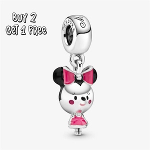 Op de afbeelding: Een zilveren bedel met een Minnie Mouse-ontwerp. De bedel heeft een Minnie Mouse-hoofd met zwarte oren, een roze strik en een roze jurk. De bedel heeft het Pandora-logo en de tekst "BUY 2 GET 1 FREE".