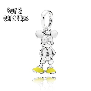 Pode incluir: Um berloque de Mickey Mouse prateado com sapatos amarelos. O berloque é feito de metal brilhante e tem uma argola na parte superior para prender a uma pulseira ou colar. O texto "BUY 2 GET 1 FREE" está no canto superior esquerdo.