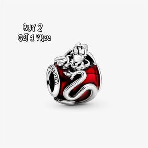 May include: A Pandora charm with a red enamel base and a silver dragon design. The charm features a dragon wrapped around the red sphere, with a dragon figure on top. The word "Pandora" is visible on the side of the charm.