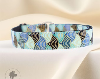 Könnte beinhalten: Ein Hundehalsband mit einem sich wiederholenden Muster aus blauen, schwarzen und goldenen Halbkreisen. Das Halsband hat eine schwarze Innenseite und eine silberne Metallschnalle. Der Hintergrund ist ein weicher, cremefarbener Stoff.