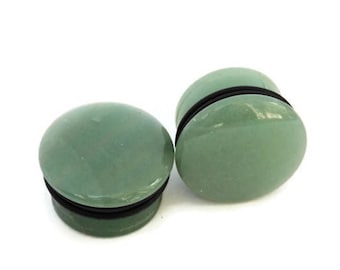Puede incluir: Par de medidores de oreja de piedra verde con anillos de goma negros.