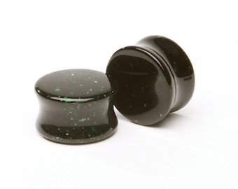Puede incluir: Par de dilatadores de oreja negros y verdes con un patrón moteado.