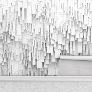 May include: A white wall with a 3D textured design of rectangular shapes. A roll of wallpaper is partially unrolled, revealing the plain wall underneath. The room has a white skirting board and a concrete floor.