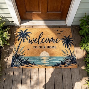 May include: A rectangular doormat with a beach scene. The mat features a sunset over the ocean, palm trees, and the words "welcome to our home" in black script. The background is tan, with blue and navy accents.