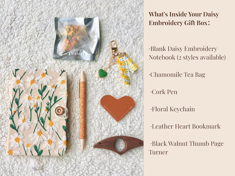 May include: An overhead shot of a gift box's contents, including a daisy-embroidered notebook, chamomile tea bag, cork pen, floral keychain, leather heart bookmark, and a black walnut thumb page turner. The text reads "What's Inside Your Daisy Embroidery Gift Box:"