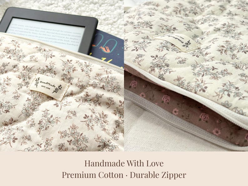 May include: Cream-colored quilted fabric case with a floral pattern, holding an e-reader and a book. The case has a durable zipper and a small tag that says "handmade with love". The bottom of the case is a dark brown fabric with a rose pattern.