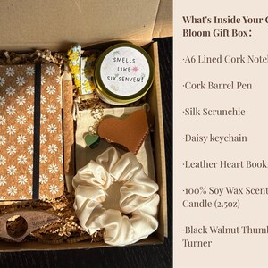 May include: A gift box filled with a cork notebook, pen, scrunchie, keychain, bookmark, candle, and page turner. The notebook has a daisy pattern. The candle reads "Smells Like Six Senven!"