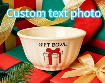 Op de afbeelding: Een crèmekleurige cadeaukom met de tekst "GIFT BOWL" en een cadeauverpakking. De kom staat tegen een achtergrond van ingepakte cadeaus in rood en groen, met gouden linten en de tekst "Custom text photo".