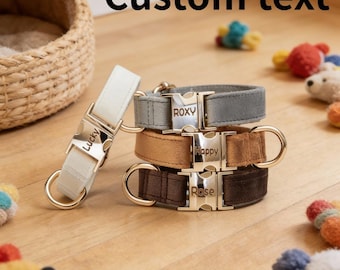 May include: A stack of personalized dog collars in gray, tan, and brown suede. Each collar has a gold-colored buckle with a name engraved on it. The text "Custom text" is at the top of the image.