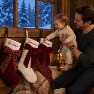 Peut inclure: Trois chaussettes de Noël suspendues. La première est en velours rouge matelassé avec un nœud écossais. La deuxième est en velours blanc avec un grand nœud rouge. La troisième est à carreaux rouges et verts avec un nœud rouge. Le nom Genevieve est brodé.