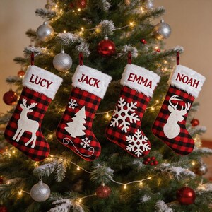 Könnte beinhalten: Vier Weihnachtsstrümpfe mit rot-schwarzem Karomuster und weißen Kunstfellbündchen. Jeder Strumpf ist mit den gestickten Namen LUCY, JACK, EMMA und NOAH personalisiert und mit weißen Filzmotiven wie Rentieren, Tannenbäumen und Schneeflocken verziert.