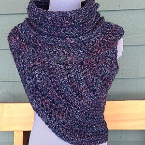 Könnte beinhalten: Ein gehäkelter Schal in einer dunkelblauen und rosafarbenen Farbkombination. Der Schal ist mit einem strukturierten Stich gearbeitet und hat einen hohen Kragen.