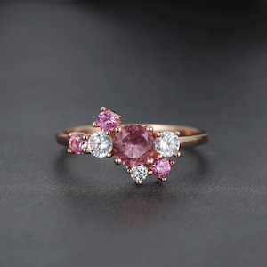 Peut inclure: Bague en or rose ornée d'un groupe de pierres précieuses. La bague présente une grosse pierre centrale rose et ronde, entourée de petites pierres roses et blanches. Le métal est de couleur or rose chaud.