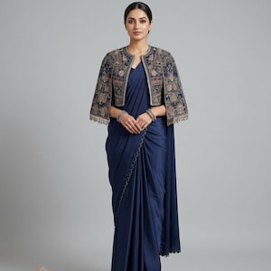 May include: A navy blue saree and a matching embroidered jacket. The jacket has detailed floral patterns in gold, brown, and blue, with beaded fringe. The saree has a scalloped edge.