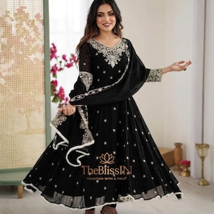 May include: Black embroidered Anarkali suit with a matching dupatta. The suit features intricate silver embroidery on the neckline, sleeves, and hem. The dress has a flared silhouette and is adorned with small star-shaped embellishments. The BlissIN logo is visible.