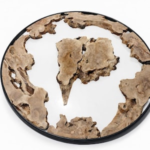 Op de afbeelding: Ronde spiegel met een zwart metalen frame. Het oppervlak van de spiegel wordt omgeven door onregelmatig gevormde stukken lichtbruin hout. De houten stukken creëren een unieke, organische rand rond het reflecterende oppervlak.