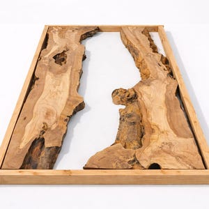 May include: A rectangular wooden wall art piece with a natural wood grain design. The artwork features two organic-shaped wooden sections with a white space in between, framed by a light brown wooden border.