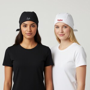 Puede incluir: Dos mujeres con camisetas negras y blancas y gorras a juego. La gorra negra tiene el nombre "Lyla" bordado en blanco, mientras que la gorra blanca tiene "Hailee" en rojo. Las gorras est&aacute;n atadas por detr&aacute;s.