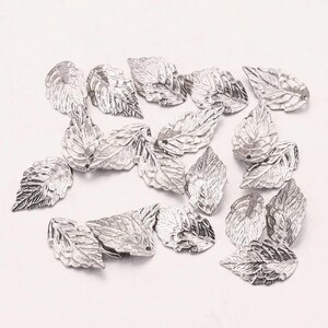 May include: Silver-coloured metal leaf charms with detailed veining. These decorative leaves are ideal for jewellery making, scrapbooking, or other craft projects. The charms are approximately 2.5 cm in length.