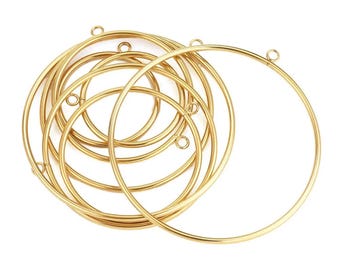 May include: A collection of gold-coloured metal hoop rings, each with a small loop at the top for attaching to other items. The hoops are of varying sizes and are arranged in a pile, with some overlapping. The background is plain white.