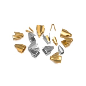 May include: A collection of gold and silver metal findings, including clasps and connectors, are arranged on a white background. The pieces are diverse in shape and size, with some resembling curved clips and others small, open tubes.