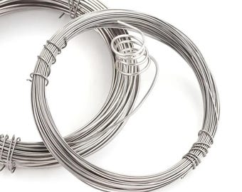 May include: Two coils of silver-colored wire are displayed against a white background. The wire is tightly wound into circular shapes, with one coil partially wrapped and secured. The wire appears to be thin and flexible, suitable for crafting or jewelry making.
